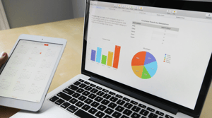 A computer showing two graphs and an iPad showing a calendar