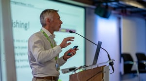 UNIwise employee speaking in a microphone in front of a big screen