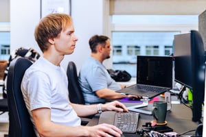 The image shows two men sittingg at their desks working at the UNIwise office