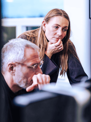 UNIwise employees, Rikke and Simon, looking at a complex task in the office