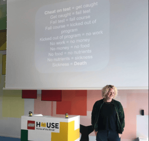 The image shows a woman presenten in front of a big projector screen