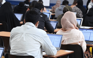 Multi-cultural students taking digital assessment on their laptops in an exam hall