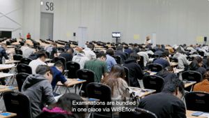 Students taking a pen and paper exam in a large exam hall
